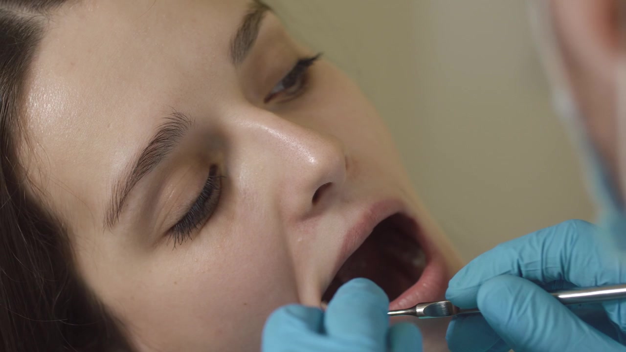 Dentist Examining Patient Teeth with Dental Mirror and Probe