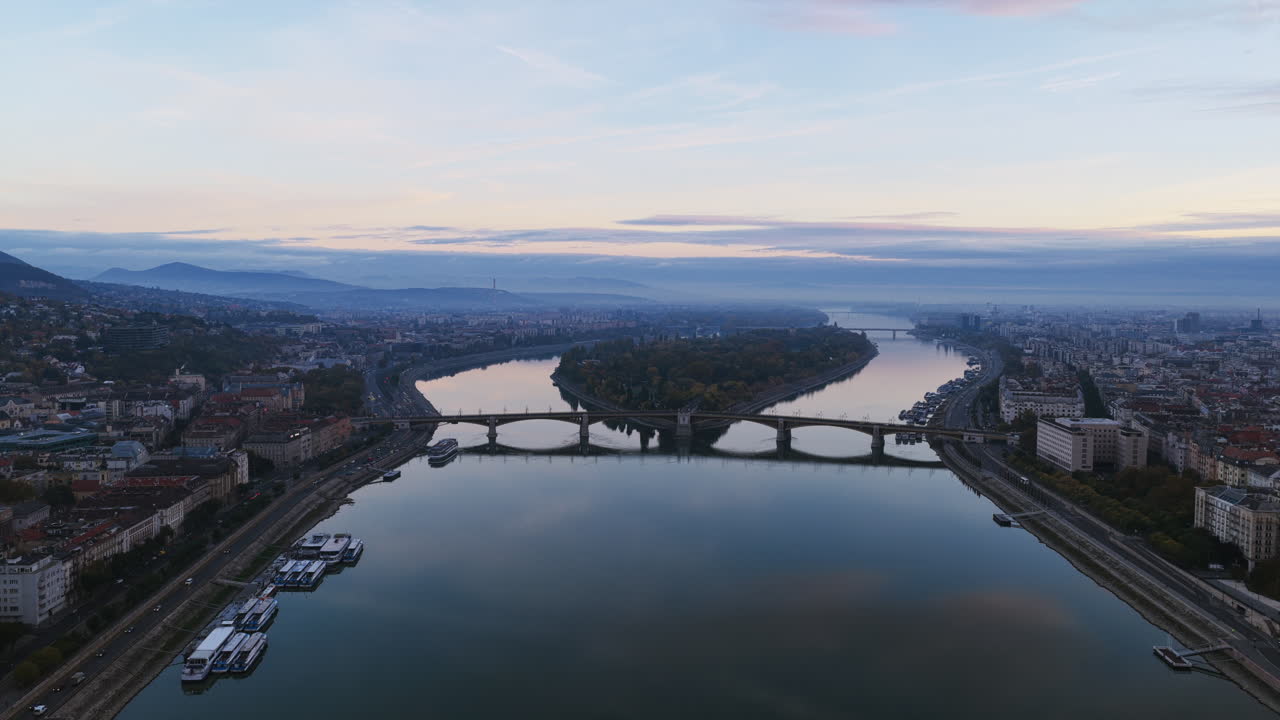 Morning light reveals Margaret Island and the Danube bridges linking Buda and Pest, framed by soft hills and calm reflections