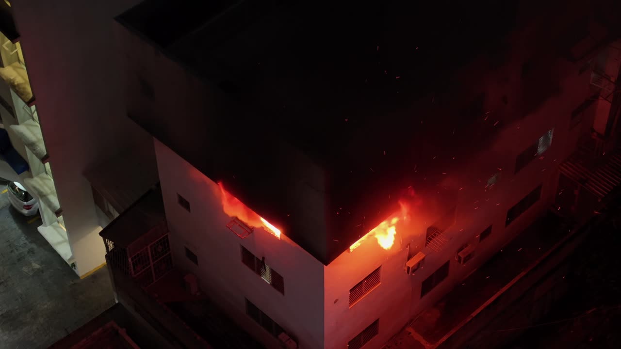 Apartment Building Engulfed in Flames with Smoke and Fire Pouring from Two Windows at Night