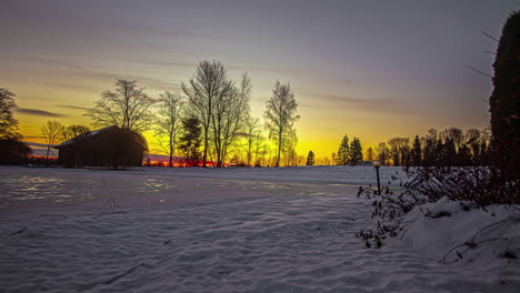 Static-shot-of-a-beautiful-wooden-cottage-covered-with-thick-layer-of-white-snow-with-sun-rising-from-behind-clouds-in-timelapse-at-sunrise