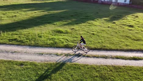 Luftaufnahmen-Eines-Mannes,-Der-An-Einem-Sonnigen-Sommertag-Sein-Fahrrad-Auf-Einer-Landstraße-Reitet