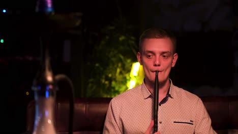 man smoking hookah in a night club