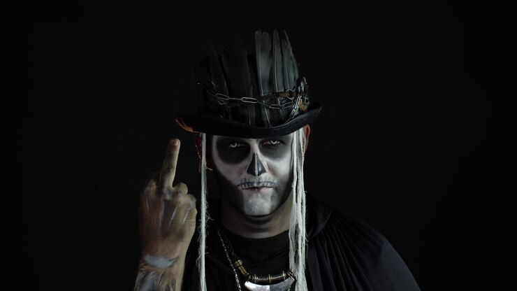 Uomo sinistro con trucco da teschio che fa smorfie e mostra il dito medio. Gesto maleducato. Halloween.
