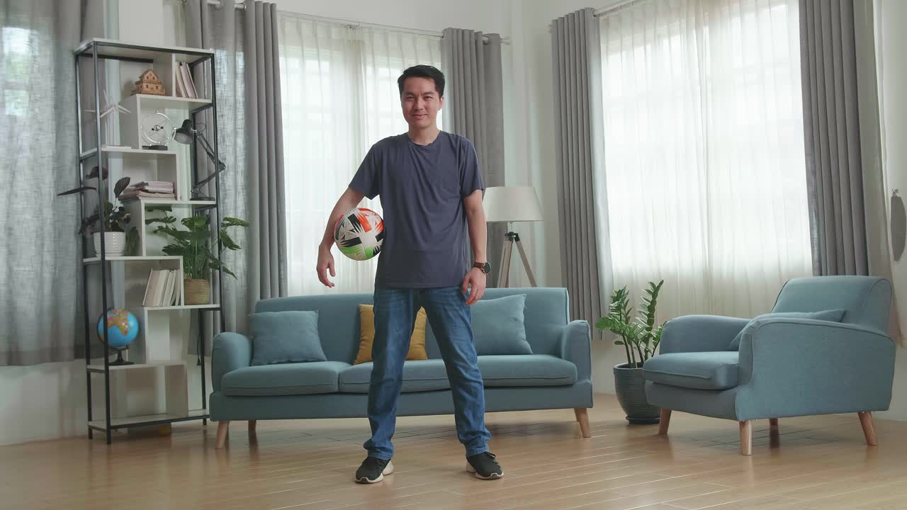 Asian Man With Soccer Ball In Living Room