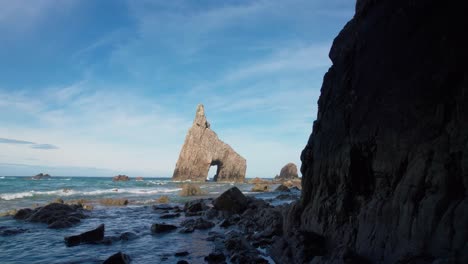 Dolly-stabilized-moving-backwards-entering-the-cave-on-the-beach-of-Campiechos-in-Asturias-with-the-sea-arch-in-the-background-located-in-the-north-of-Spain