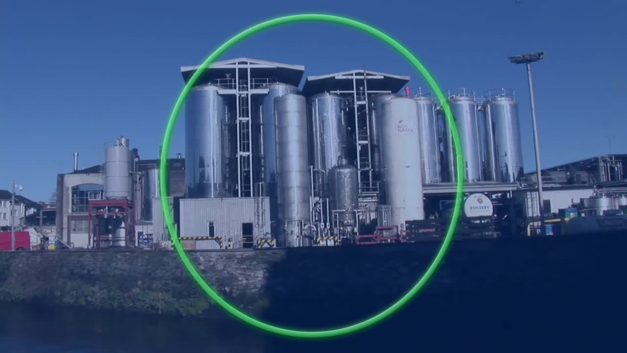 Green circle animation over industrial factory with large metal silos