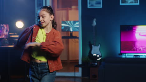 niño feliz bailando en el interior de un estudio casero débilmente iluminado, produciendo contenido para un canal en línea