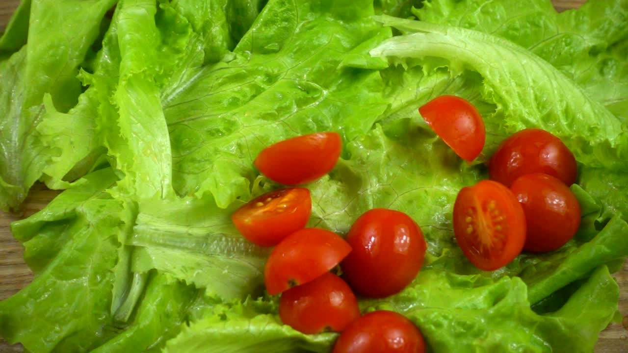 Falling of tomatoes on lettuce leaves. Slow motion