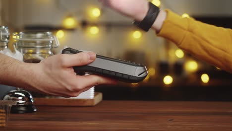 paying with smartwatch in cafe. contactless, touch-free shopping in pubs. nfc technology concept, using fitness bracelet payment via terminal close-up.