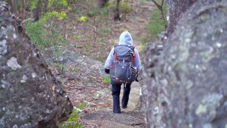 indigenous australian girl descending through two large boulders in the blue mountains national park