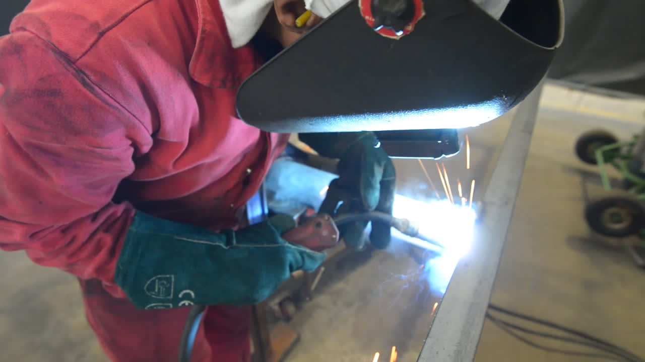 Close Up Of A Welder Welding Metal In A Steel Fabrication Plant. high angle