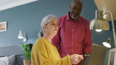 Happy-senior-diverse-couple-sitting-at-table-and-working