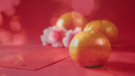 animación de naranjas y flores sobre decoraciones tradicionales chinas en fondo rojo.