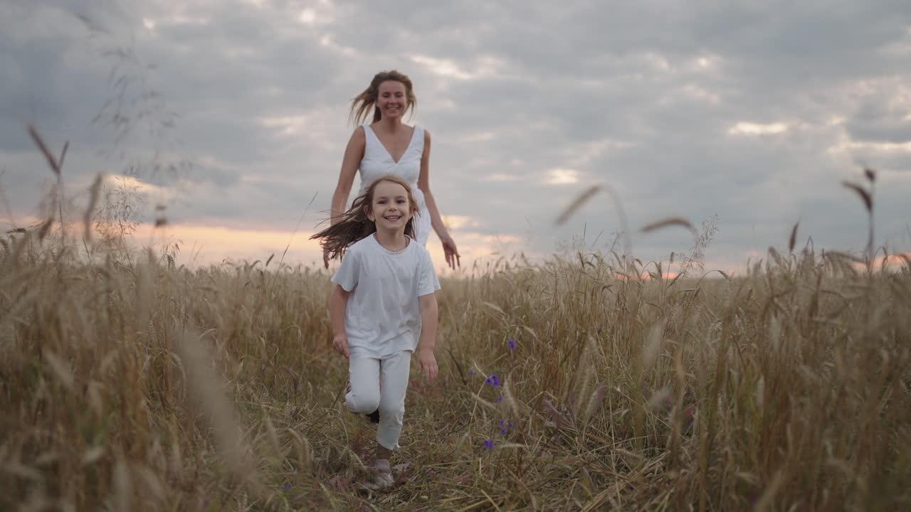 la hija y la madre sueñan juntas corriendo en el campo de trigo al atardecer. gente de familia feliz en el concepto del campo de trigo. mamá y niña jugando a correr. niño divertido corriendo en un prado verde.