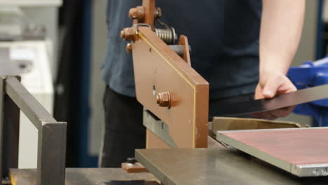 worker using a metal guillotine shear for cutting sheet metal in an industrial setting, close-up