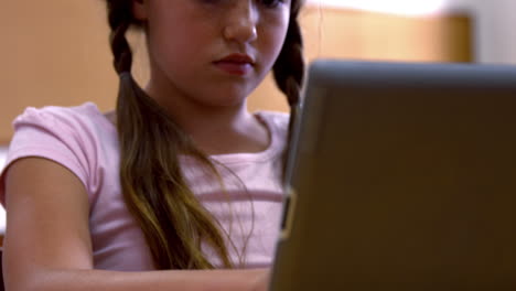 schoolgirl using tablet at desk in school