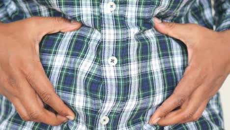 a man holding his stomach in a plaid shirt