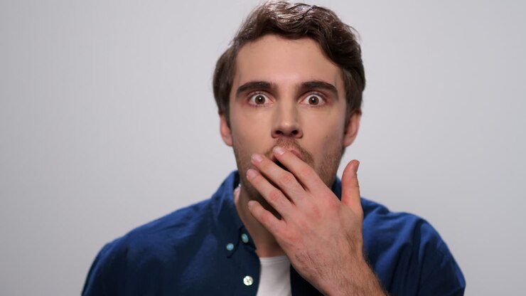 Surprised man looking at camera in studio. Handsome guy with wow expression