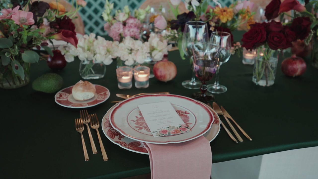 Detailed place setting with decorated plate gold cutlery candles and floral arrangement on dining table
