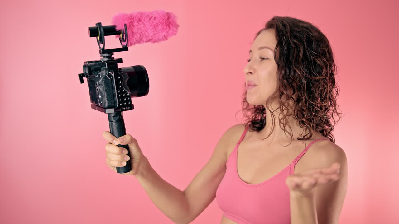 Woman vlogging against a pink background