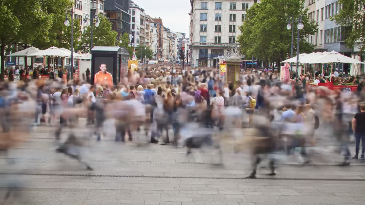 A Bustling Urban Scene Captured in Motion: Busy Pedestrians Fill the Plaza, Interacting Amidst the Energy of City Life, Showcasing Movement and Vibrancy.