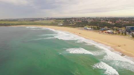 Panorámica-Desde-Arriba-De-Los-Surfistas-Esperando-Una-Ola-A-La-Playa