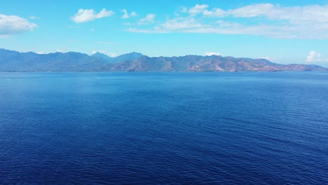 Espacio-Marino-Azul-Panorámico-Bordeado-Por-Altas-Montañas-De-Islas-Bajo-Un-Cielo-Brillante-Con-Nubes-Blancas-Congeladas-En-Indonesia