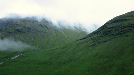 Panning-drone-shot-of-the-clouds-flow-through-mountain-peak