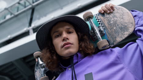 young skater man looking camera outdoor. guy thinking about new trick outside.