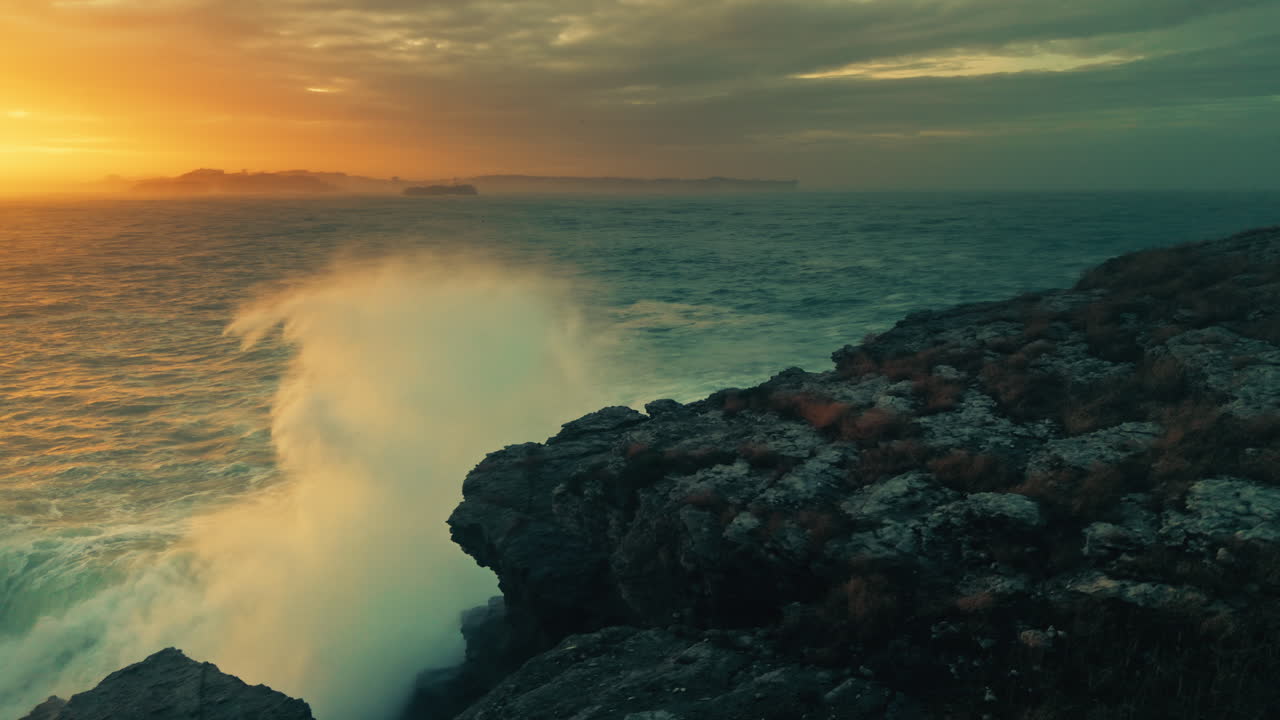 Onde oceaniche spettacolari che si infrangono contro una scogliera rocciosa al tramonto