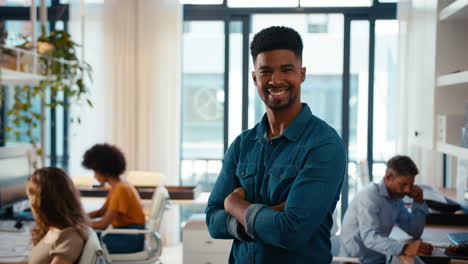 Portrait-Of-Young-Smiling-Businessman-Standing-In-Modern-Office