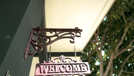 ornate metal welcome sign hanging on a house