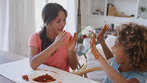 Close-up-of-two-girlfriends-having-fun-playing-with-modelling-clay-at-home,-elevated-view