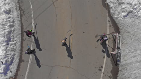 Vista-Panorámica-De-Niños-Jugando-Al-Hockey-En-Las-Calles-Cubiertas-De-Nieve-En-Una-Zona-Residencial,-Antena-De-Drones