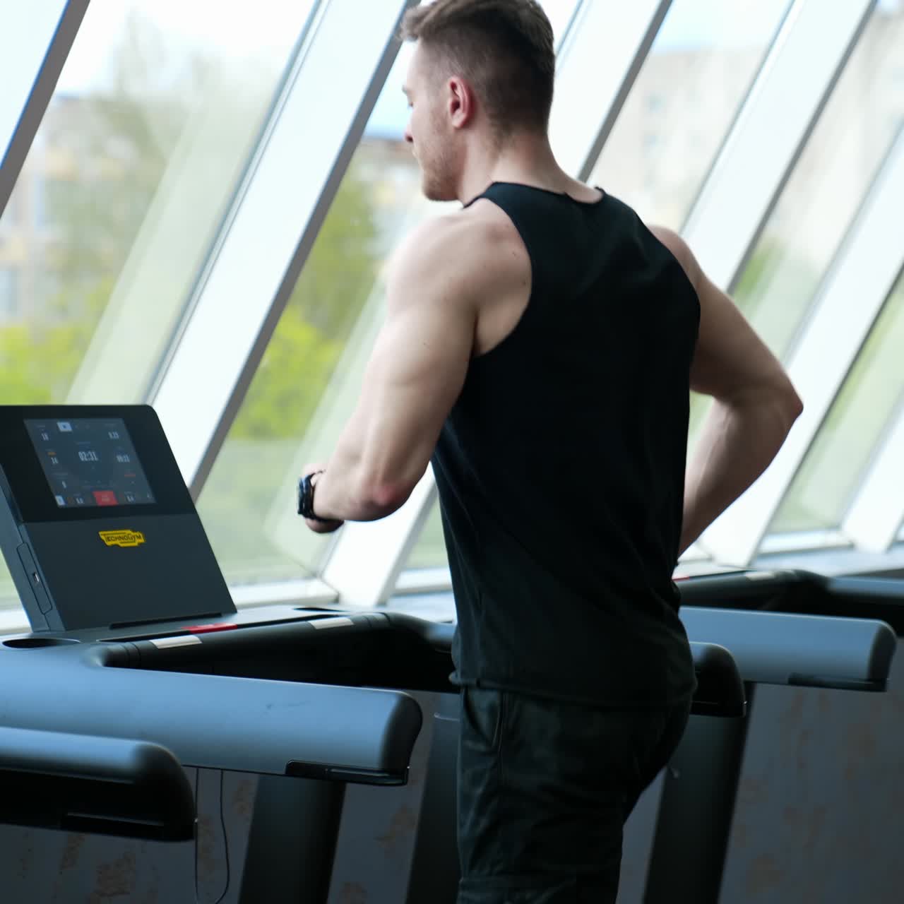 Adam spor kulübünde bacak çalışıyor. Genç atletik adam spor salonunda koşu bandında koşuyor.