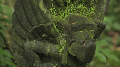 Old-stone-statue-of-Hindu-god-at-Ubud-Monkey-Forest,-close-descending-pedestal