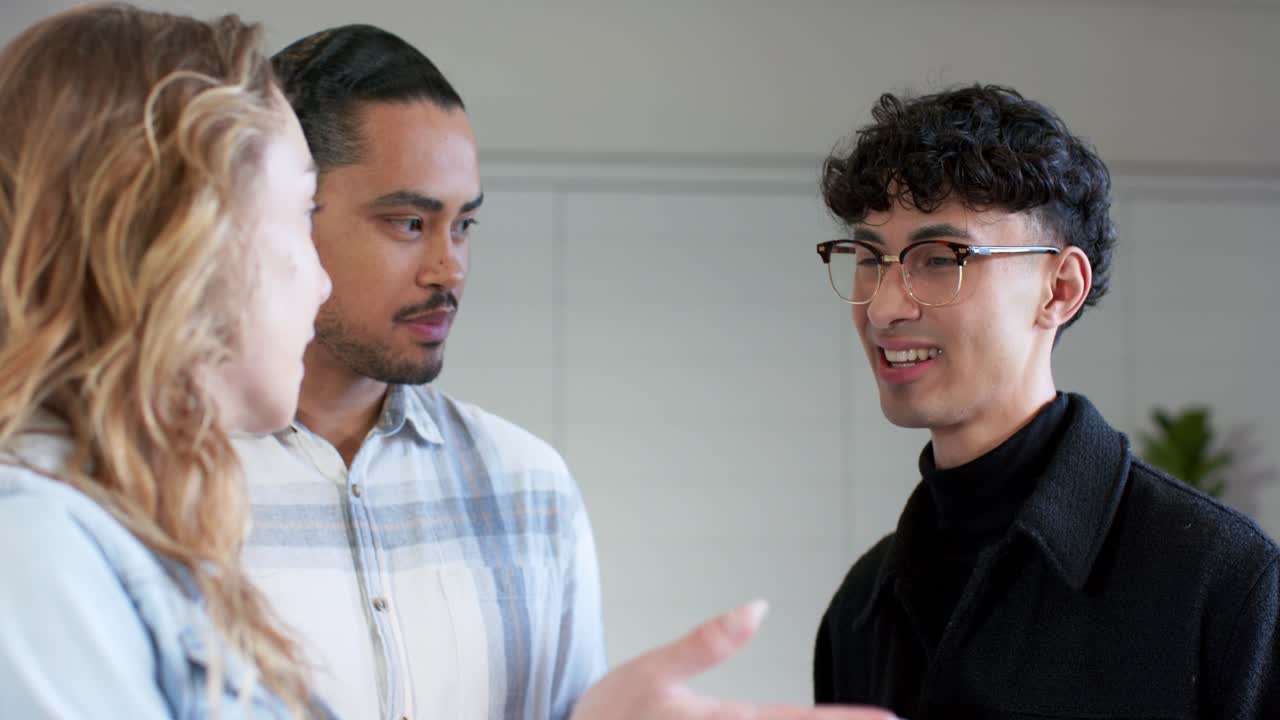 Diverse coworkers examining smartphone in office after colleague holding device by storage cabinet