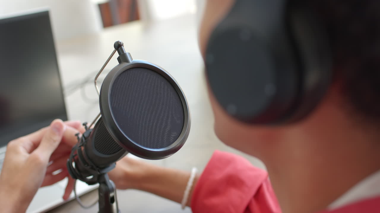 Recording podcast, teenage boy using microphone and headphones at home studio