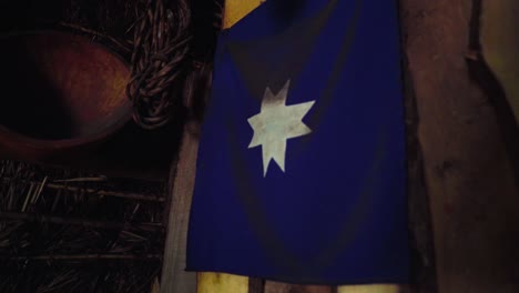 handheld of a blue guñelve mapuche flag hanging from the interior wall of a ruka traditional aboriginal house, chile