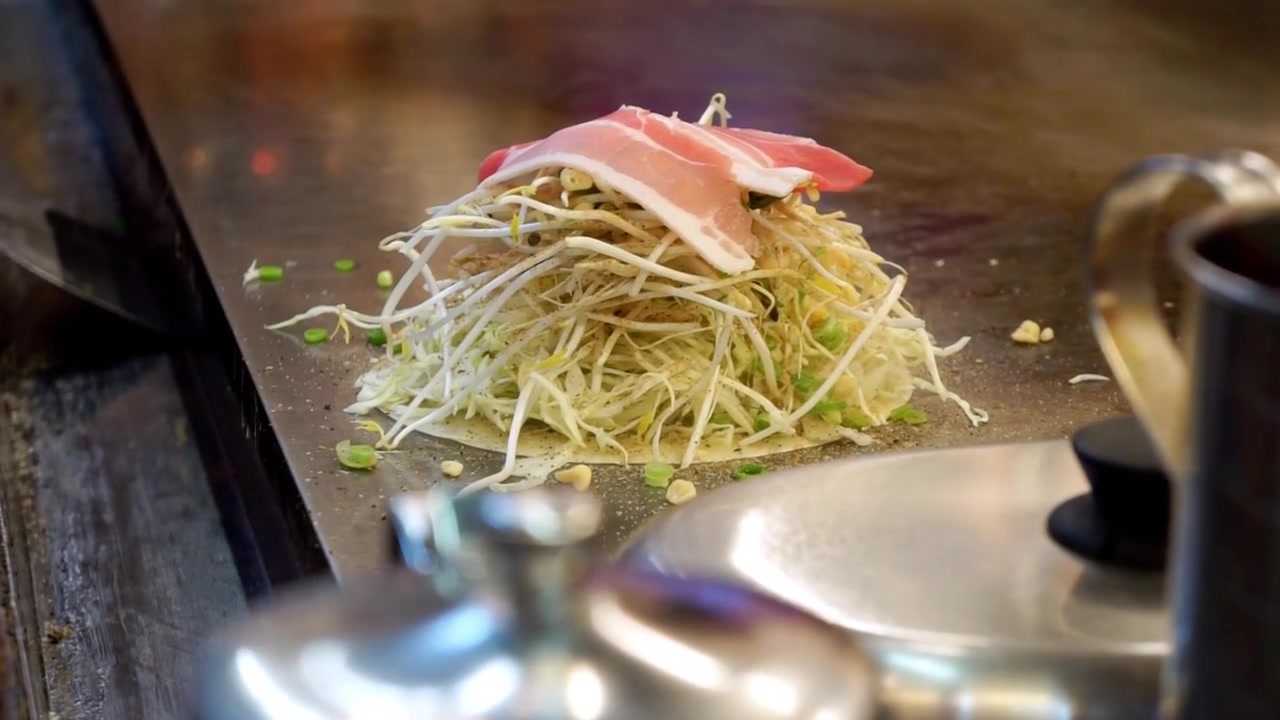 Primo piano di chef che prepara il classico Okonomiyaki giapponese in Giappone