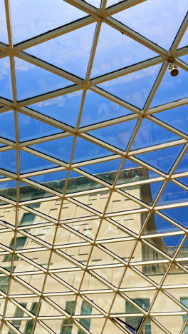 blue sky can be seen through the glass cupola roof. view on the buildings standing outside. vertical video.