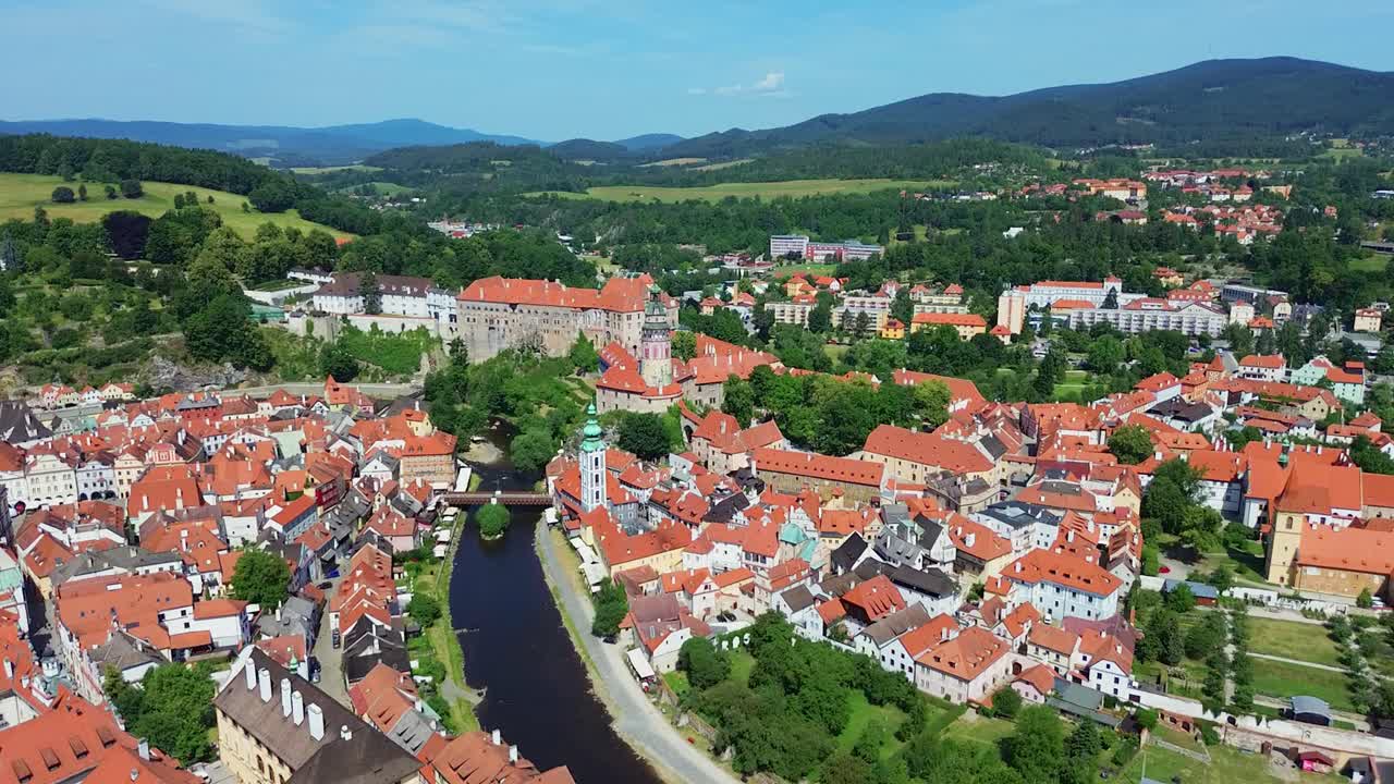 A slow flying down shot over a historic city centre. There are a bunch of old buildings and a castle in the middle. It's a sunny day with some clouds