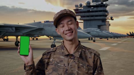 military personnel holding a green screen phone on an aircraft carrier