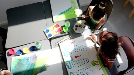 in school, children painting colorful pictures on canvases in art class