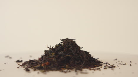 Close-up-shot-of-a-pile-of-dried-black-tea-leaves-rotating-on-bright-background