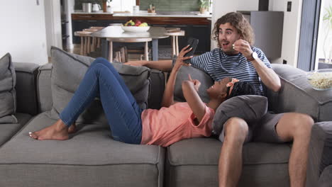 diverse couple, a young african american woman and a young caucasian man, relax on a sofa at home