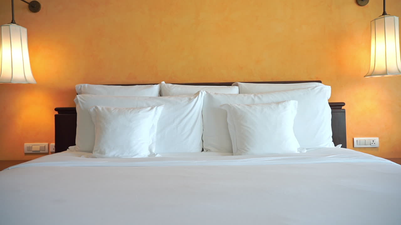 Pan across a made resort bed backed by a yellow wall