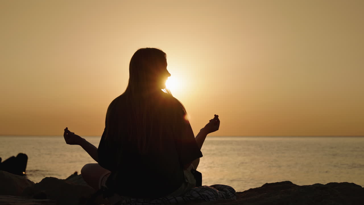 Una mujer meditando al atardecer.
