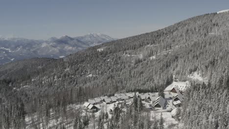 pohorje mountains in slovenia with lukov dom cabins and hotel covered in snow, aerial pan left shot