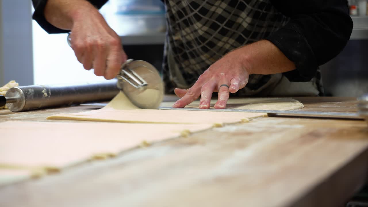 Baker measures and cuts dough for pastries, slow motion 4K